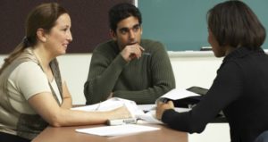 three students with writing assignment