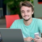 male college student with phone and laptop