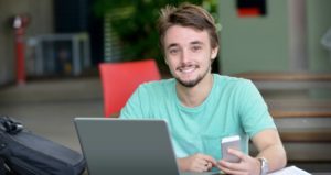 male college student with phone and laptop