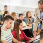 Professor helping student in lecture hall