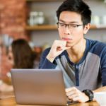 Pensive college student using laptop