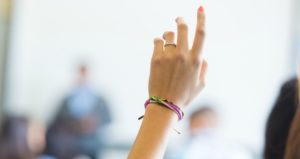 student raising hand on class