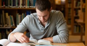 Male college student studying in library.