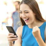 Excited student pumps her fist as she takes a quiz on her phone