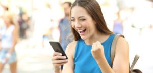 Excited student pumps her fist as she takes a quiz on her phone