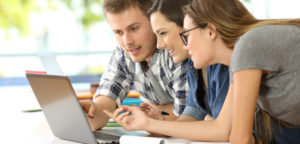 Three students working on a group exam on a laptop