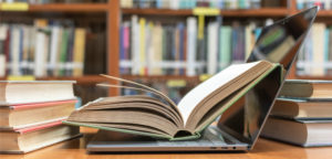 A book lies open on the keyboard of an open laptop