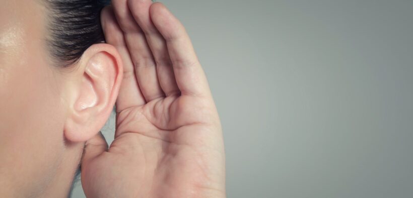 Close-up of a woman's hand cupping her ear