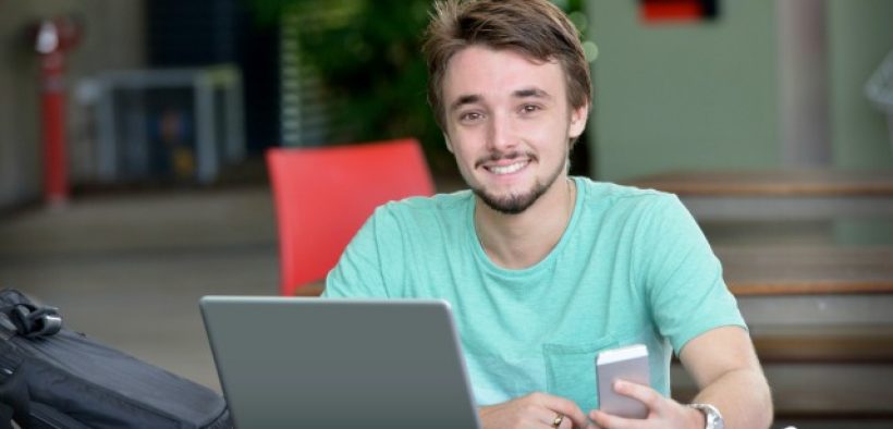 male college student with phone and laptop
